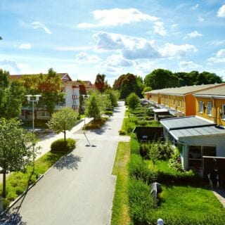 Områdesöverblick på Fredriksberg. Gula radhus mittemot flerbostadshus i färgglada fasader. 