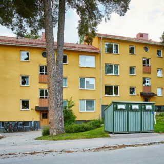 Gult lägenhetshus i tre våningar med röda balkonger