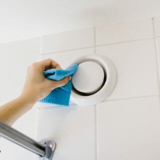 En person torkar rent en luftventil i badrummet.