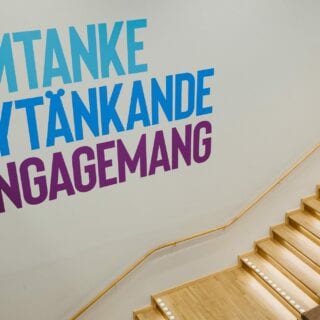 "Omtanke, Nytänkande, Engagemang" skrivet på väggen över en trappa.