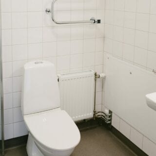 Toalett och handdukstork i helkaklat badrum.