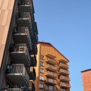Tre punkthus i brun, senapsgul och terrcotta-färgade fasader.