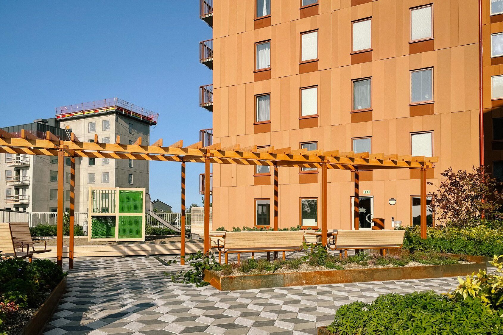 Terrass med pergola, grönytor, lekyta och matplats.