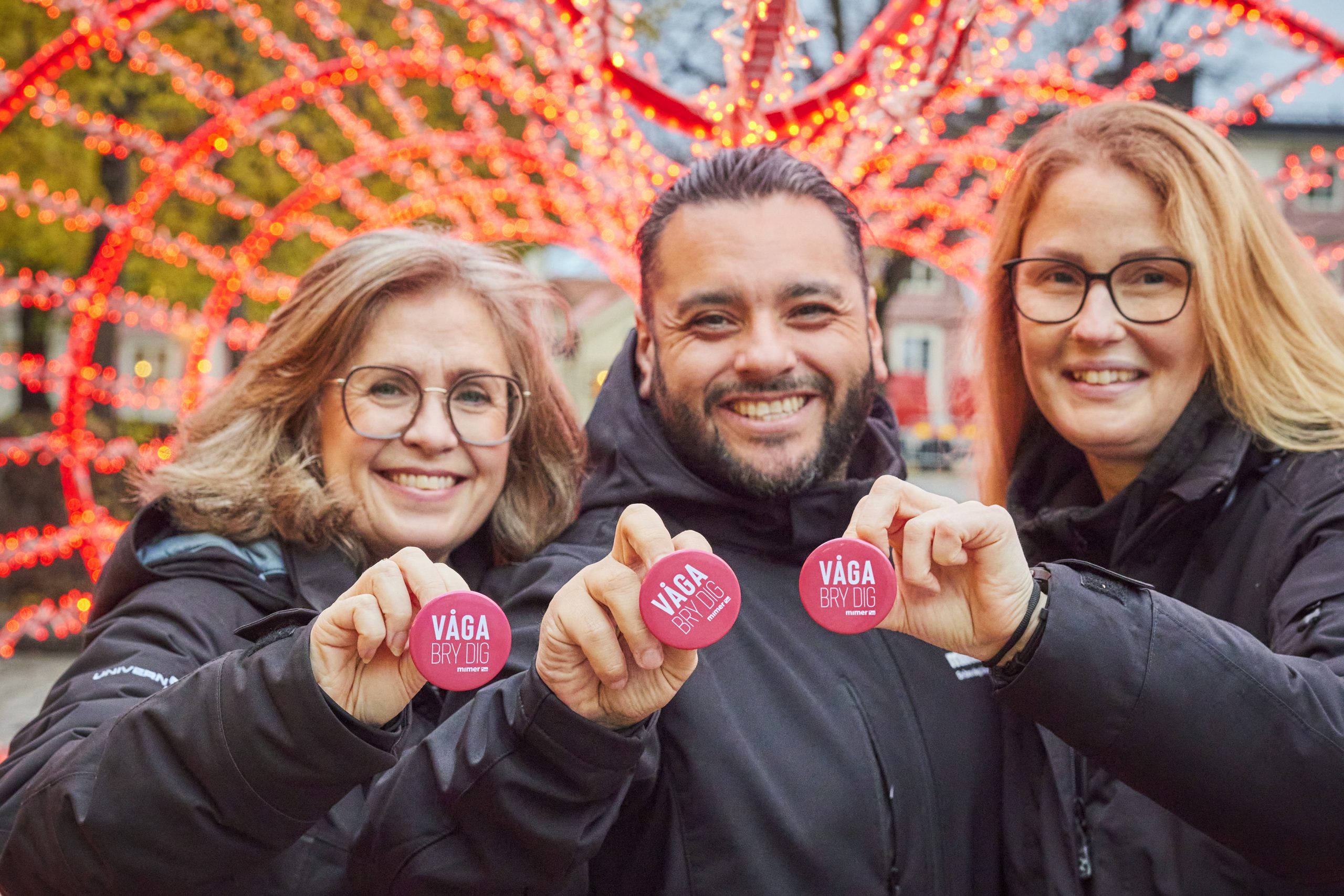 Tre medarbetare håller upp "Våga bry dig"-pins.