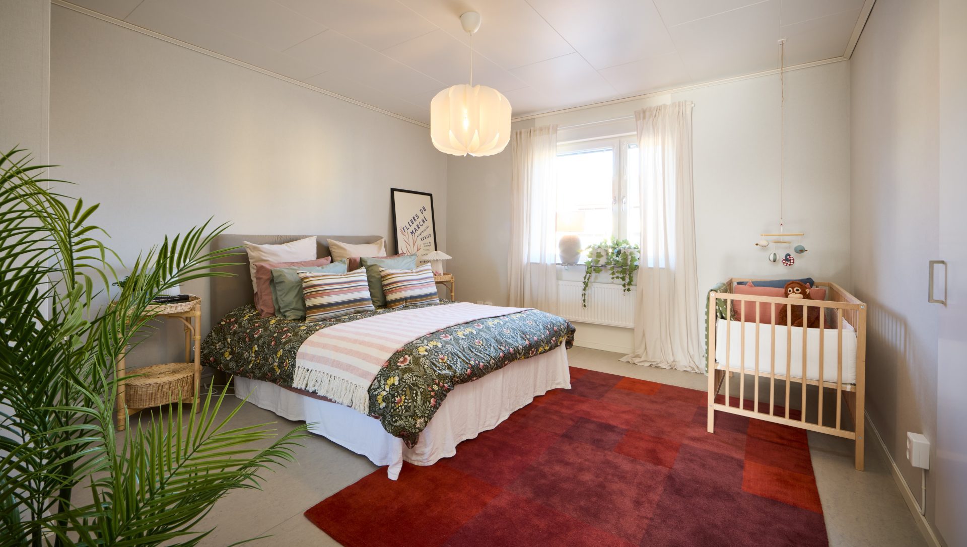 Sovrum med vita väggar, dubbelsäng och spjälsäng