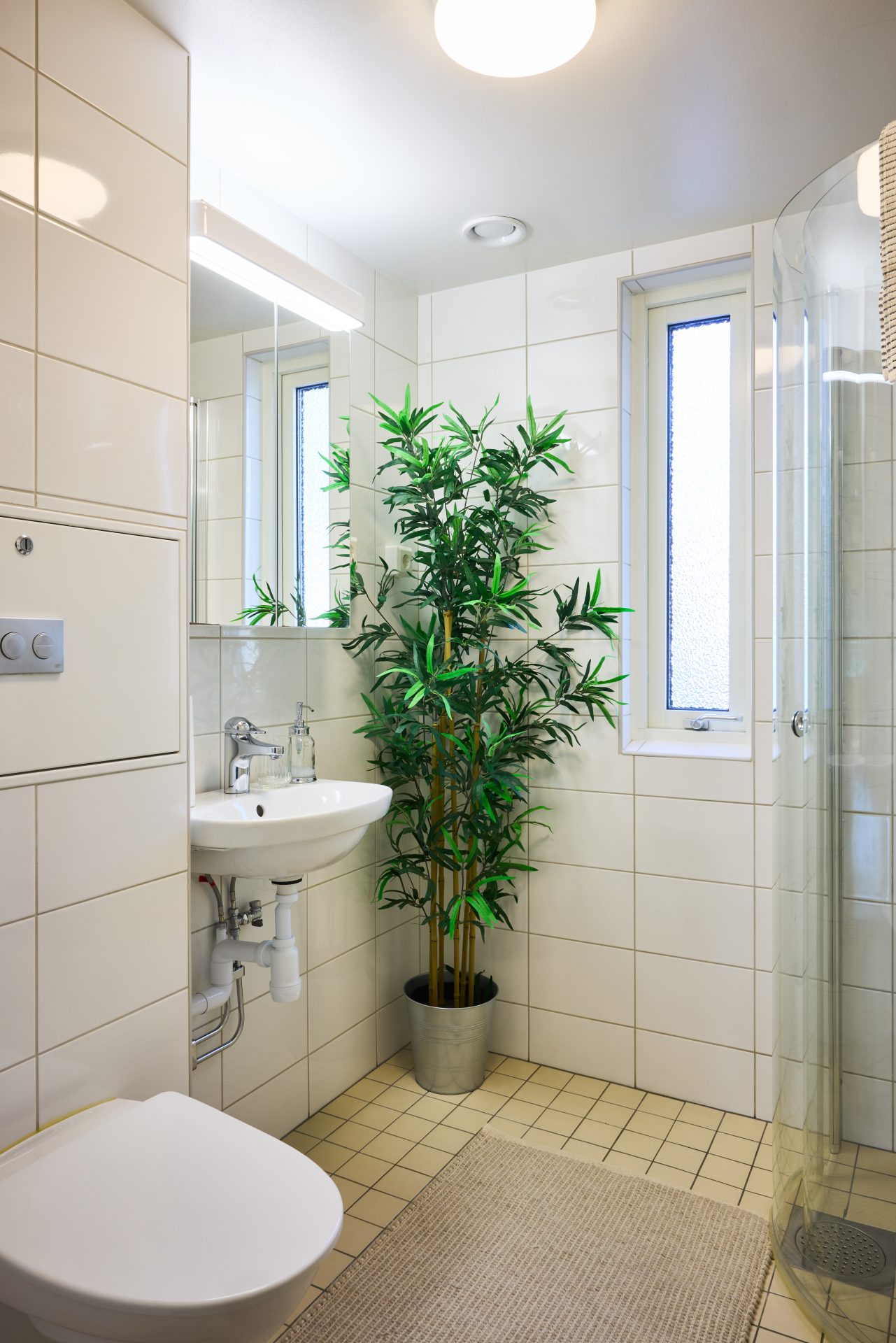 Ett badrum med en golvväxt