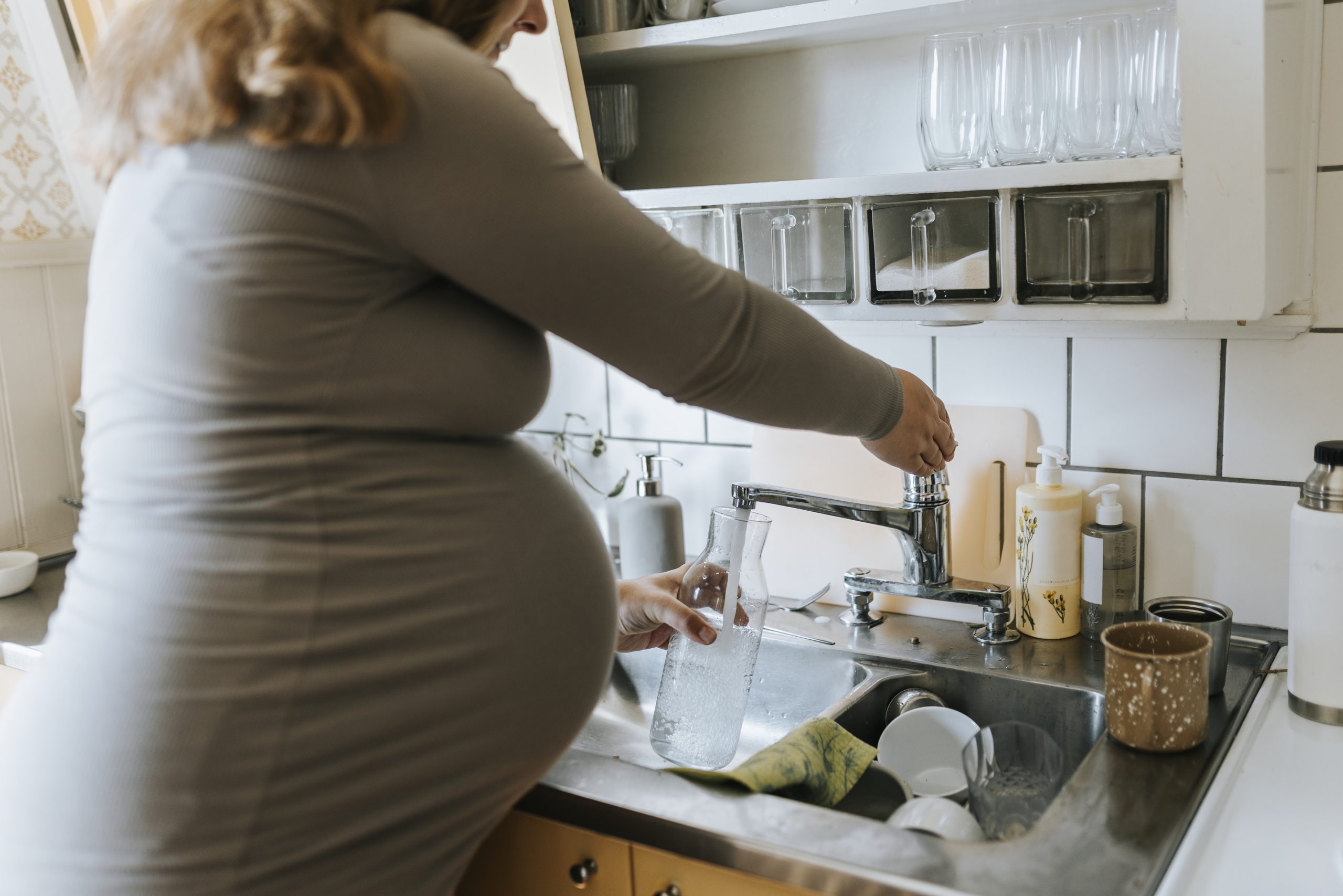 Gravid kvinna fyller vattenkanna.