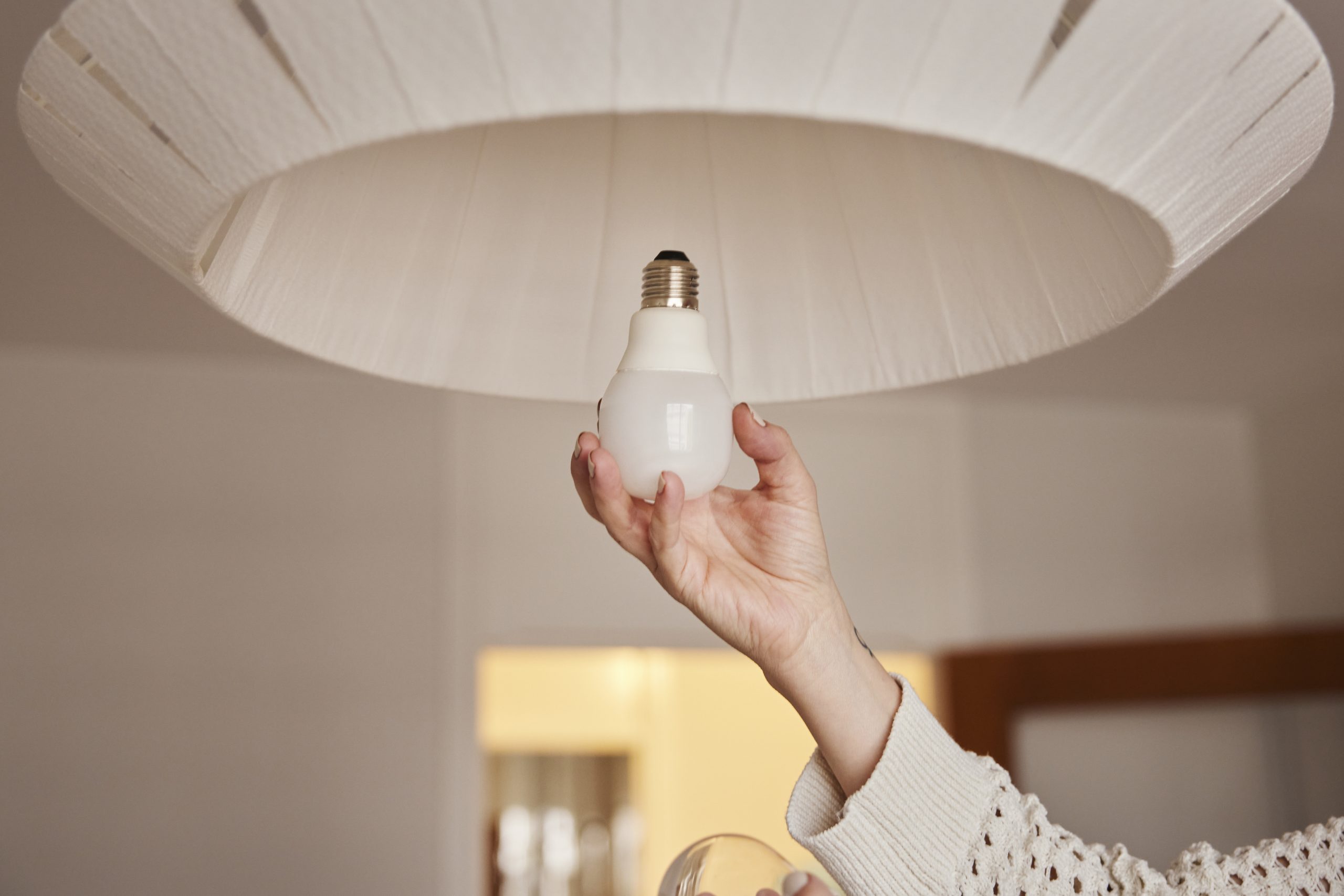 Hand som skruvar i led-lampa.